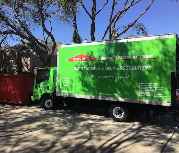 green SERVPRO box truck sitting on the road in front of a home