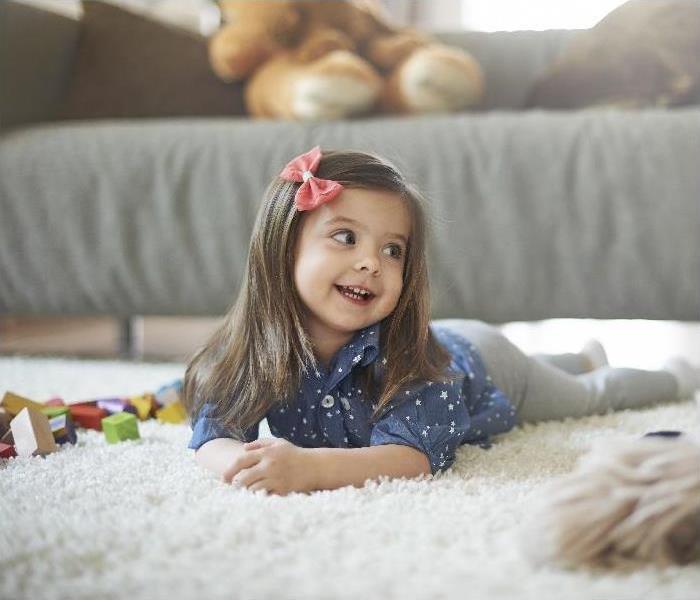 female toddler laying on carpet; toys in background