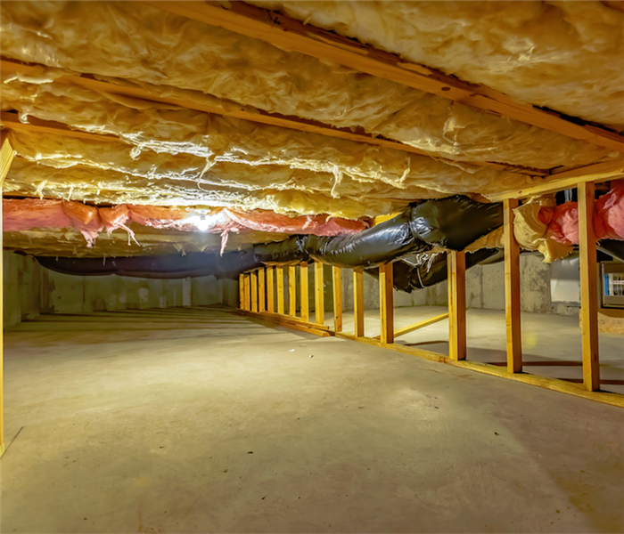 a crawlspace with wooden beams at the sides and insulation at the top