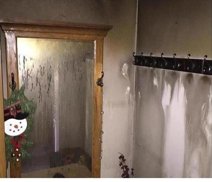 A wall in a bathroom covered in soot and smoke damage after a fire