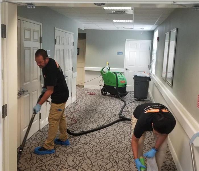 crew removing water from hallway carpeting